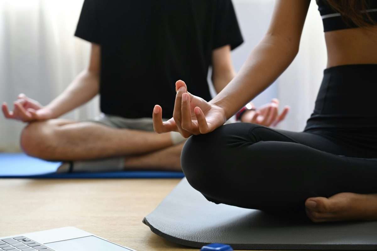 Image shows two people practicing yoga in a studio.